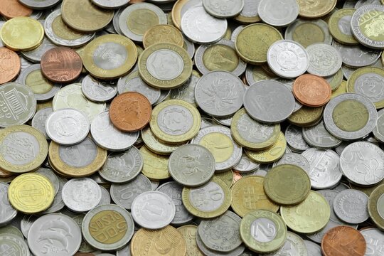 Pile of global currencies, various coin types visible up close. Different nations money together