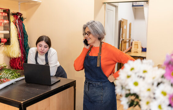 Florist assisting customer with flower order and phone call indoors