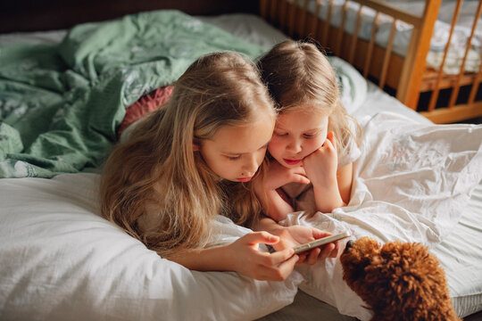 Children watching digital media together in a cozy bedroom scene