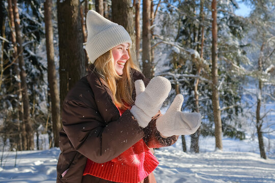 Smiling woman enjoying snowball fight in winter forest outdoors