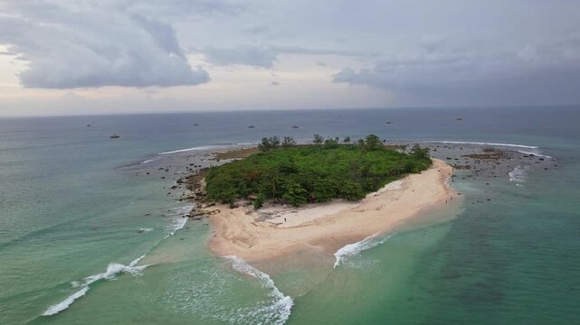 Aerial drone footage of Oar paradise small island, close to Sumur city, in Pandeglang regency, Java island, Indonesia, nearby Ujung Kulon national park, in stormy weather, blue sea and white sand