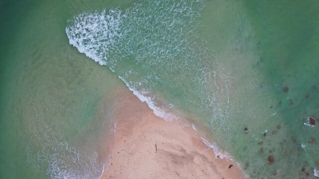 Aerial drone footage from above of Oar paradise small island beach edge, in Sumur town, Pandeglang regency, Java island, Indonesia, nearby Ujung Kulon national park, turquoise sea,white sand and waves