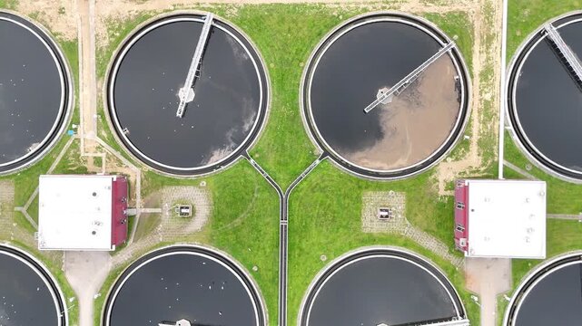 Aerial view of municipal wastewater treatment plant showing multiple circular tanks, filtration systems, and surrounding green areas, highlighting the infrastructure and operational layout of the faci