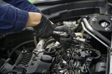 Fototapeta premium Mechanic Wearing Black Gloves Fixes Car Engine With Wrench