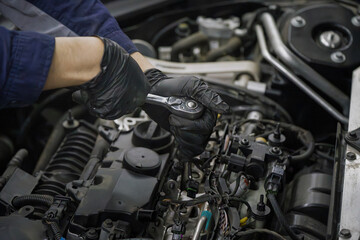 Obraz premium Mechanic in black gloves repairs engine with ratchet
