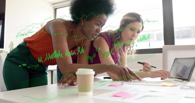 Two women at table, left woman pointing pen sparking green graphs over notes, laptop guiding sales