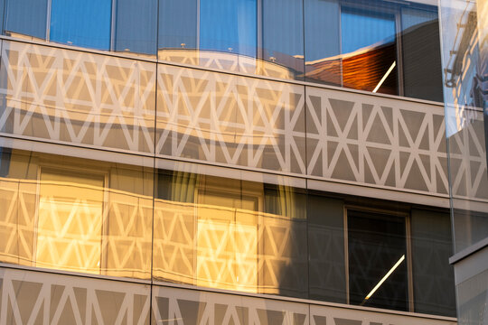 Warm urban reflection on modern building facade with rhythmic windows pattern and sleek railing showing contemporary architecture detail