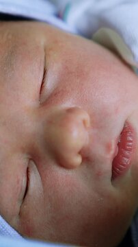 Face of a sleeping Caucasian newborn in cap. Little child sleeps tight close up. Vertical video