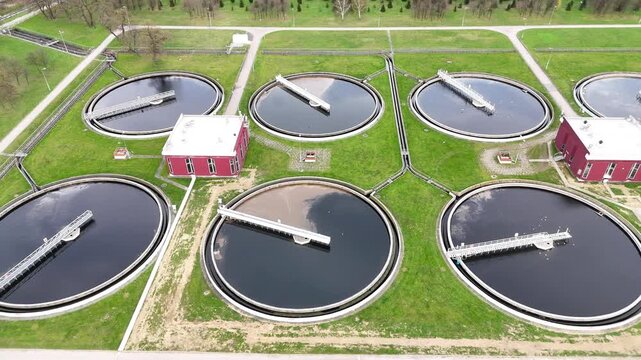 Aerial view of municipal wastewater treatment plant showing multiple circular tanks, filtration systems, and surrounding green areas, highlighting the infrastructure and operational layout of the faci