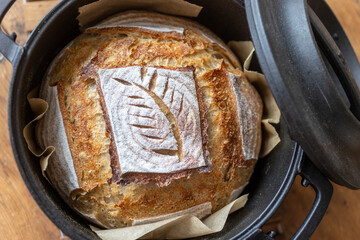 Artisan sourdough loaf with decorative scoring in a cast iron pot