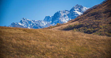 Fototapeta premium Majestic Snowy Peaks and Autumn Mountain Slopes with Copy Space