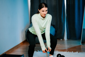 Woman lifts dumbbells at home in a fitness session during the day