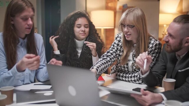 Diverse business team collaborating around laptops during a focused office discussion. Professional women and men, coworkers, colleagues or specialists reviewing information, sharing ideas, making