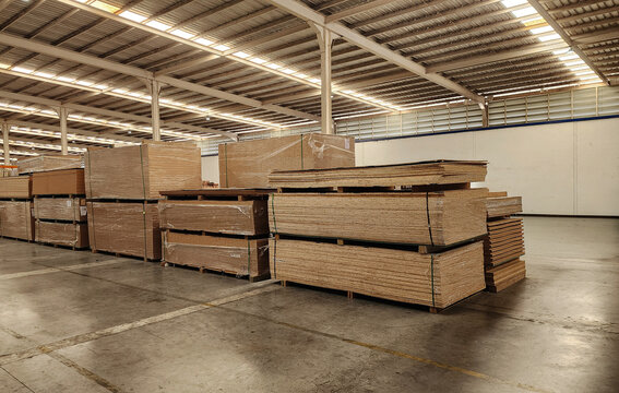 Stacks of plywood and MDF, Particle boards in a large industrial warehouse. Construction materials neatly stored for furniture manufacturing, carpentry, and building supply chain logistics.