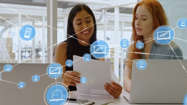 One blue icon appearing over pages and expanding into tech network while two women reviewing laptop