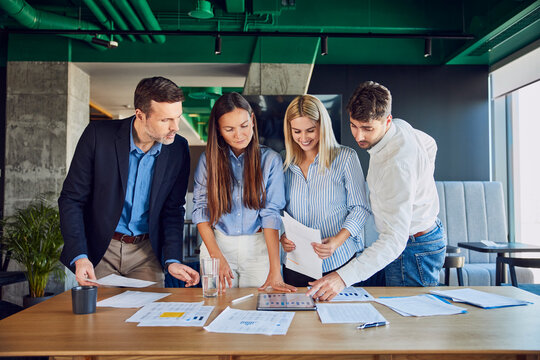 Smiling business colleagues having discussion over graphs in office