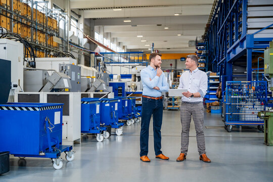 Business meeting in production hall with tablet in industrial factory