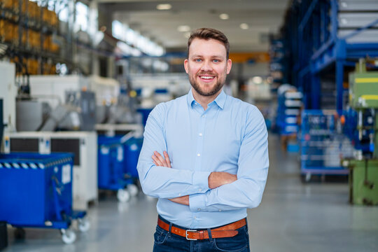 Portrait of smiling professional in production hall with arms crossed
