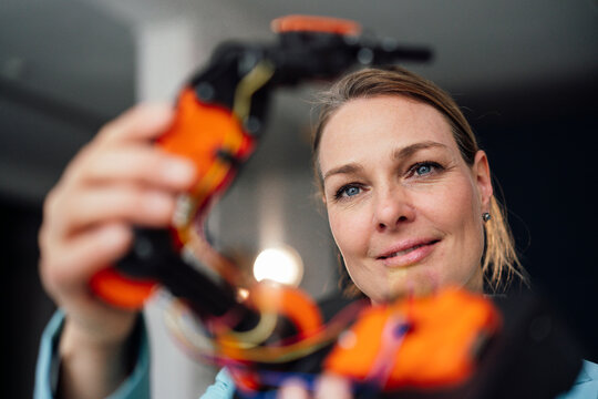 Smiling engineer analyzing robotic arm at office