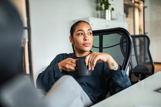 Thoughtful woman enjoying coffee at office desk