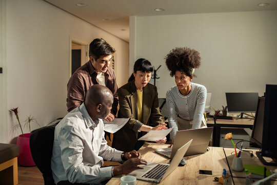 Diverse coworkers collaborating on project in modern office