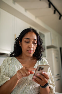 Young woman using smartphone in modern home kitchen