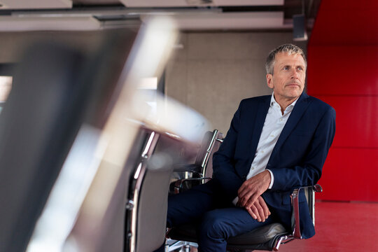 Thoughtful senior man sitting on chair in meeting room