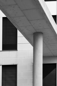 Modern building facade with concrete column and roof overhang plus windows featuring minimalist geometry creating clean abstract architecture background