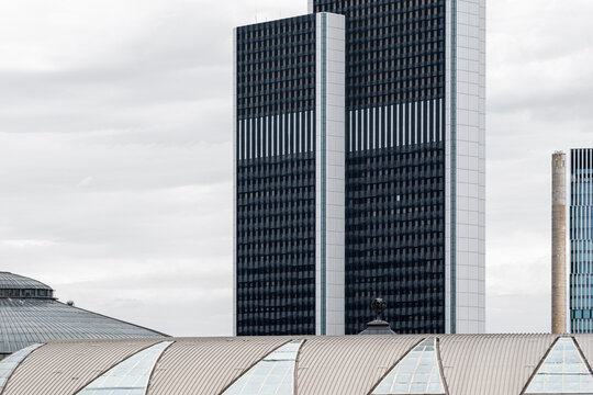 Modern urban skyscraper tower with glass facade rising in a cloudy skyline creating clean contemporary city architecture background