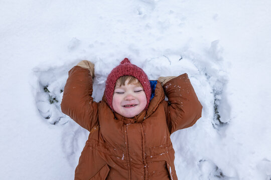 Child smiling in winter clothing playing in snow outdoors