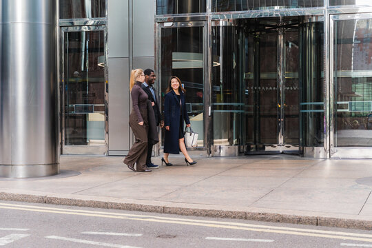 Business colleagues walking and discussing outside modern office building