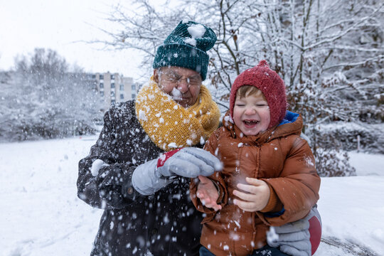 Grandfather and grandson playing outdoors in winter snow