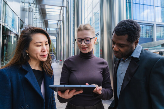 Business professionals discussing project with tablet outdoors