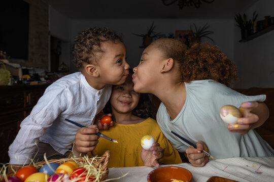 Siblings painting Easter eggs together at home during spring