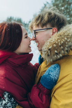 Couple smiling in winter forest wearing warm clothing in snow