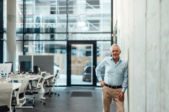 Boss in modern office standing confidently by glass wall
