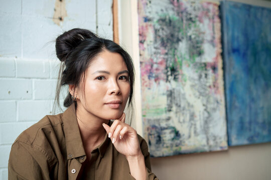 Woman with hand on chin by painting at workshop