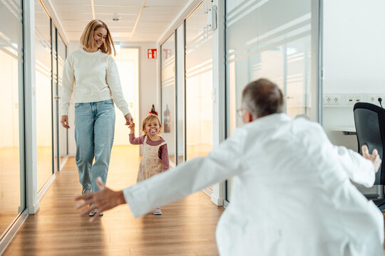 Doctor welcoming mother and child in hospital hallway