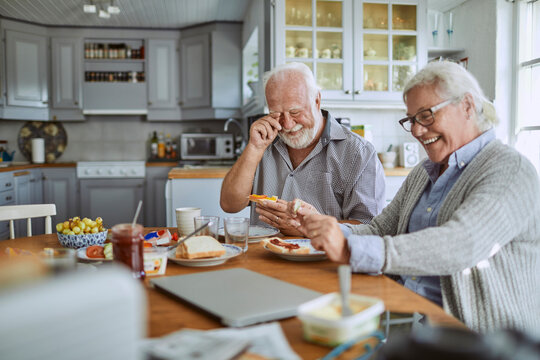 Smiling senior couple having breakfast together in home kitchen