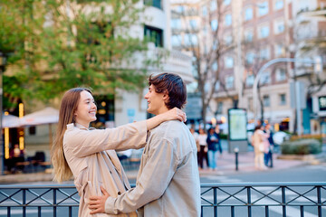 Fototapeta premium Happy young couple embracing and laughing together on a city street, enjoying a moment of affection and connection outdoors