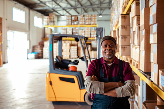 Confident warehouse worker with forklift in distribution center