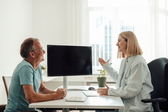 Doctor and patient talking at desk during indoor counseling session