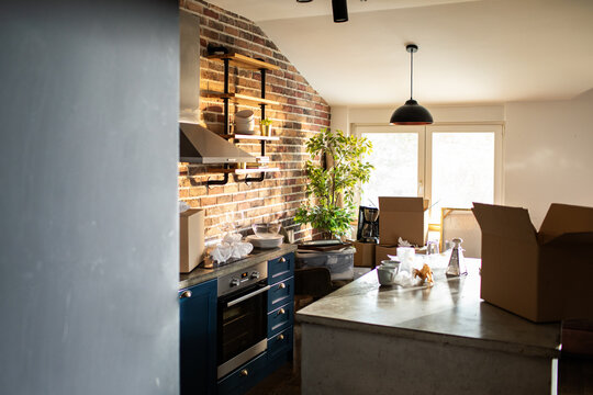 Modern apartment kitchen with moving boxes during unpacking