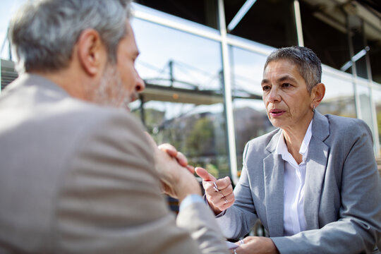 Two senior business professionals discussing work at outdoor cafe