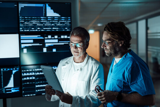 Medical professionals analyze data on tablet in hospital