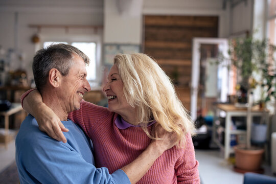 Cheerful loving senior woman with arms around man at home