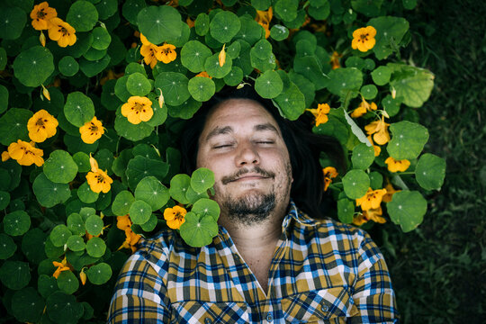 Smiling farmer lying down amidst plants with eyes closed