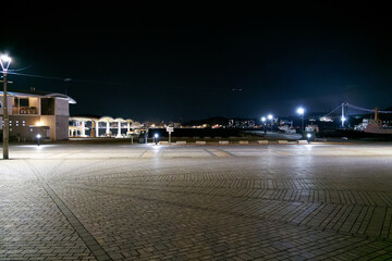 Night cityscape of a seaside plaza with cobblestone pavement and distant bridge lights in Japan. © SIOU CYUAN LIANG