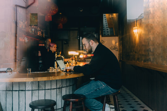 Freelancer working on laptop analyzing crypto chart at a cafe bar