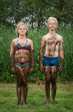 Muddy brother and sister standing outdoors in the Netherlands